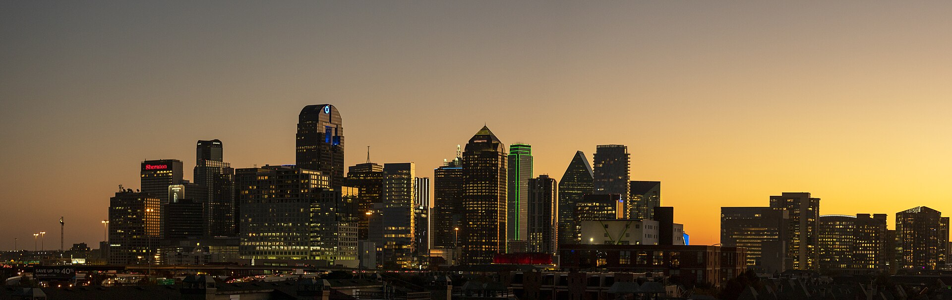 The Dallas skyline illuminated against an orange sunset
